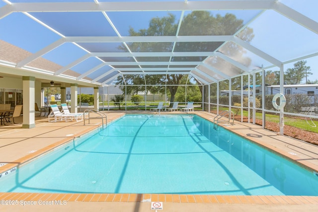 outdoor pool with ceiling fan, glass enclosure, a patio area, and fence