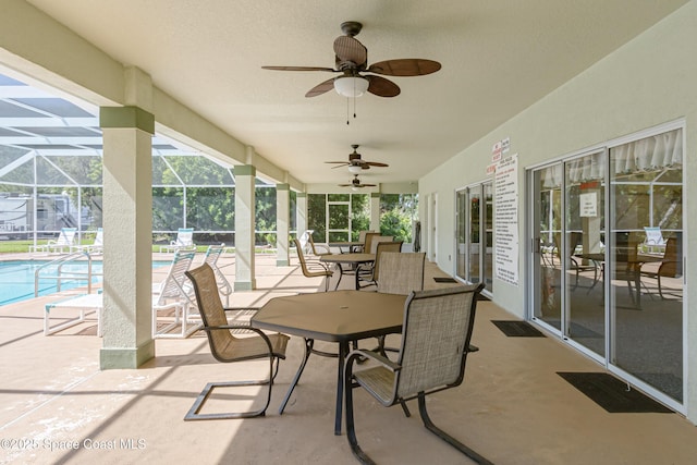 view of patio with a ceiling fan, glass enclosure, and an outdoor pool