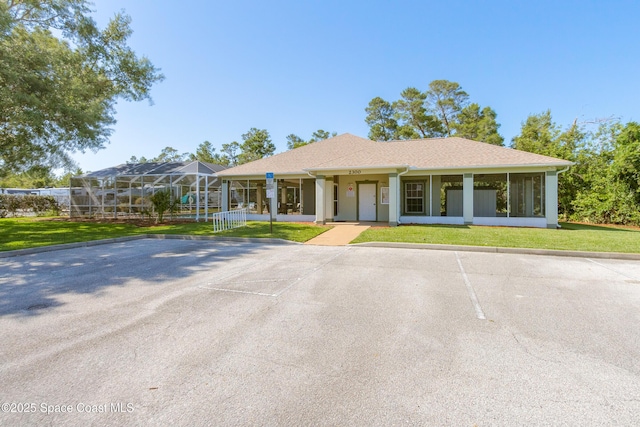 view of front facade with uncovered parking and a front lawn