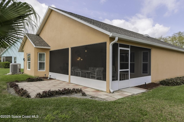 rear view of property with a sunroom, central AC, and stucco siding