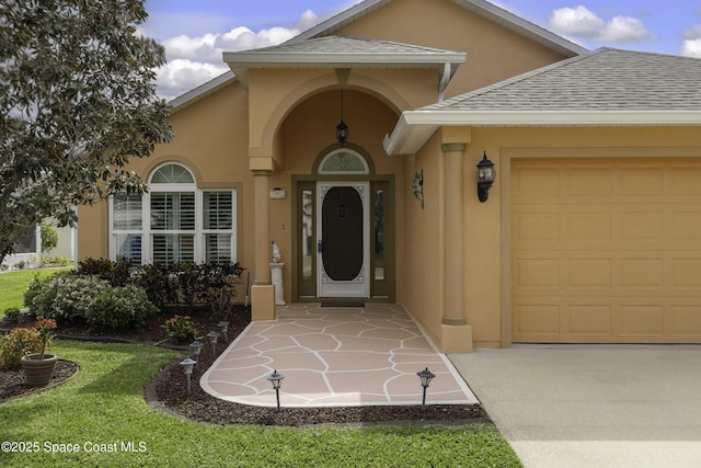 property entrance with a garage, roof with shingles, and stucco siding