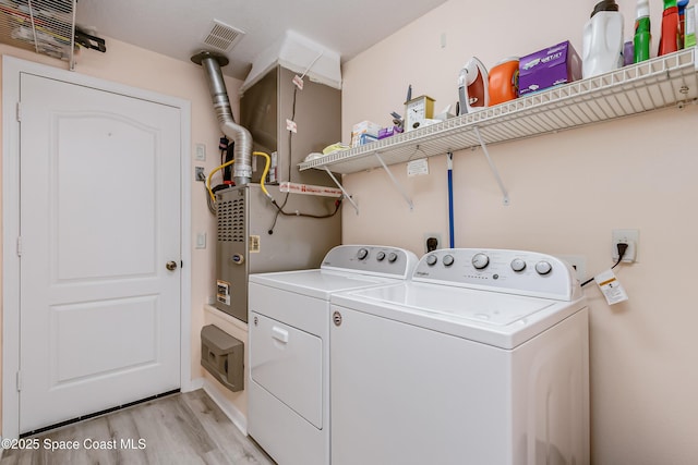 washroom with laundry area, visible vents, light wood finished floors, and separate washer and dryer