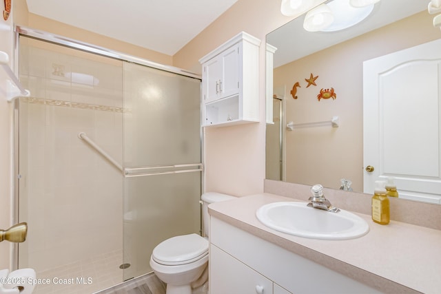 bathroom with tiled shower, vanity, and toilet