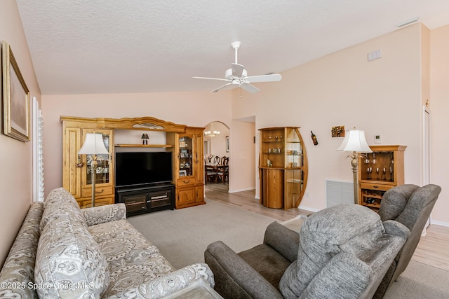 living area with lofted ceiling, visible vents, ceiling fan, a textured ceiling, and baseboards