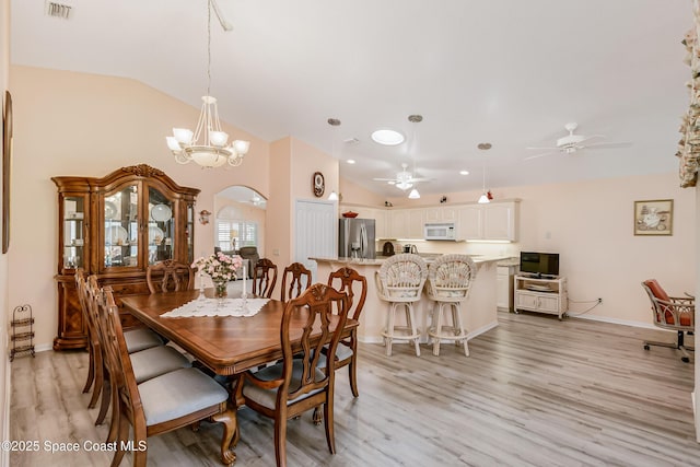 dining space featuring arched walkways, visible vents, lofted ceiling, and light wood finished floors