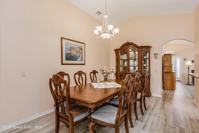 dining area featuring arched walkways, lofted ceiling, visible vents, light wood-style flooring, and an inviting chandelier