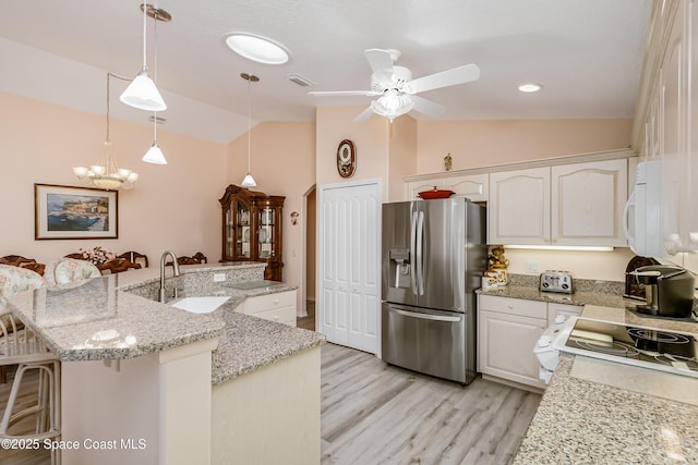 kitchen with a breakfast bar, light wood finished floors, visible vents, a sink, and white appliances