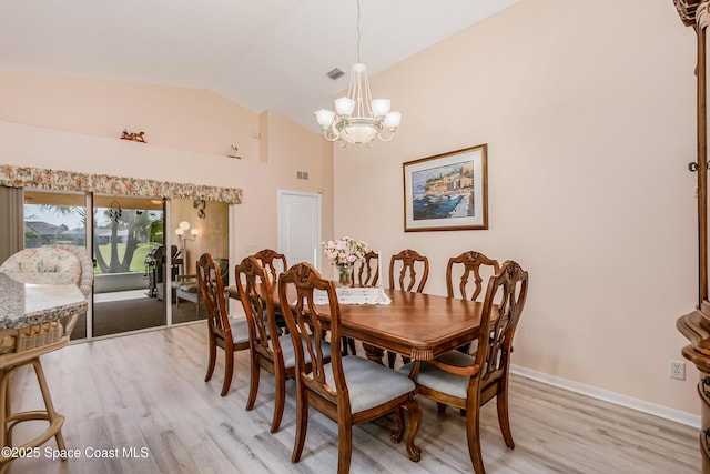 dining space with light wood finished floors, visible vents, baseboards, vaulted ceiling, and a notable chandelier