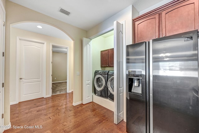 kitchen with separate washer and dryer, wood finished floors, visible vents, baseboards, and stainless steel fridge