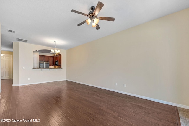 unfurnished living room featuring dark wood-style floors, visible vents, baseboards, and ceiling fan with notable chandelier