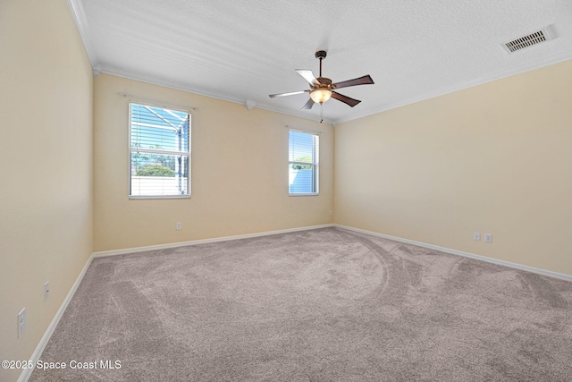 spare room featuring visible vents, ornamental molding, carpet flooring, a textured ceiling, and baseboards