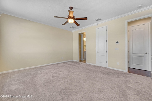 unfurnished bedroom featuring carpet floors, crown molding, visible vents, a textured ceiling, and baseboards