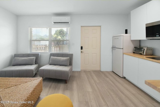 living area with light wood-type flooring, a wall unit AC, and a toaster