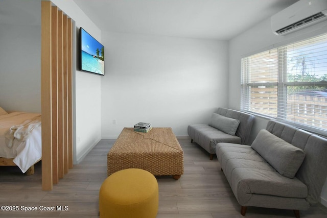 living room featuring baseboards, a wall unit AC, and light wood-style floors