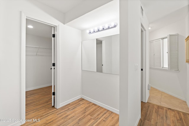 hall featuring light wood-type flooring, visible vents, baseboards, and recessed lighting