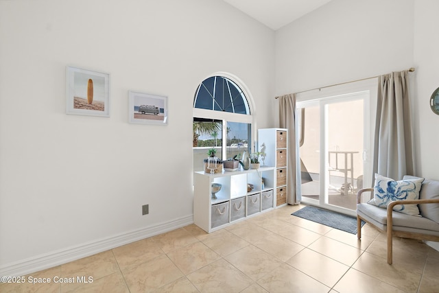 sitting room with a towering ceiling, tile patterned flooring, and baseboards