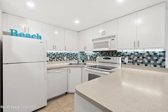 kitchen with white appliances, backsplash, a sink, and white cabinetry