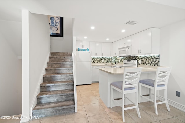 kitchen with light countertops, backsplash, white cabinetry, white appliances, and a peninsula