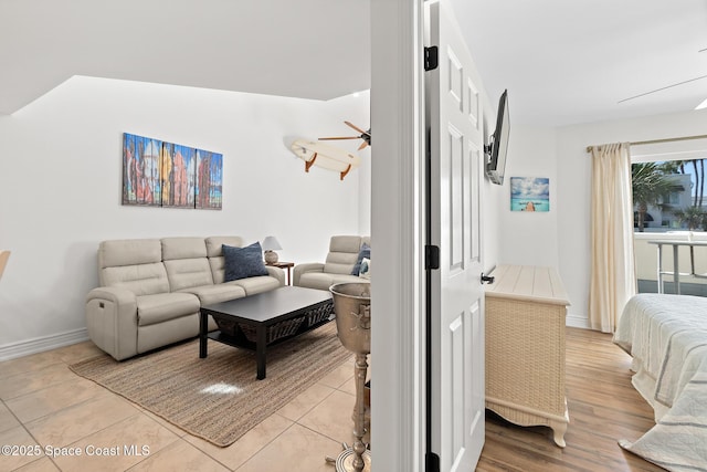 living room featuring a ceiling fan, light tile patterned flooring, and baseboards