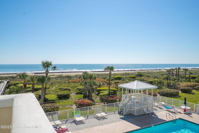 exterior space featuring a view of the beach and fence