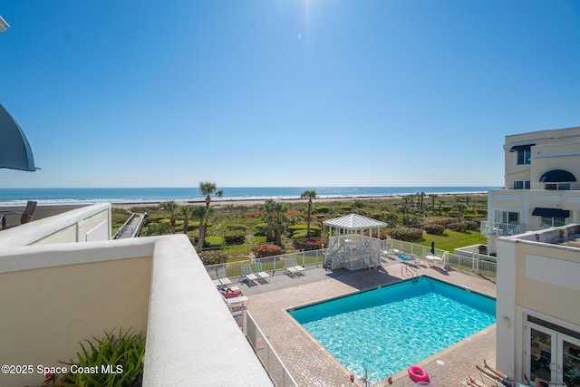 pool with a patio area, a water view, and fence