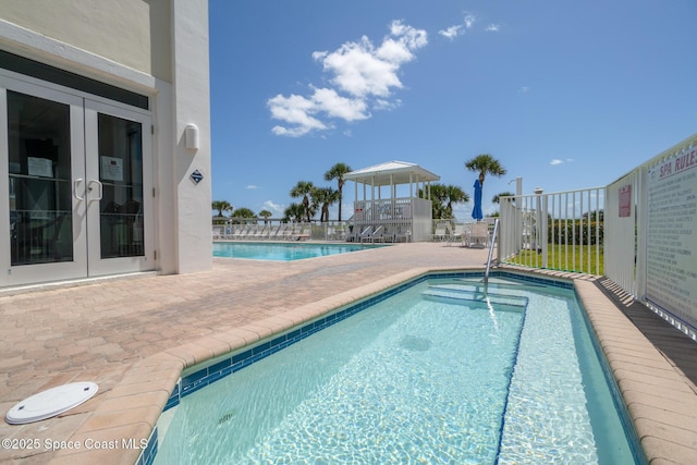 community pool with french doors and a patio area