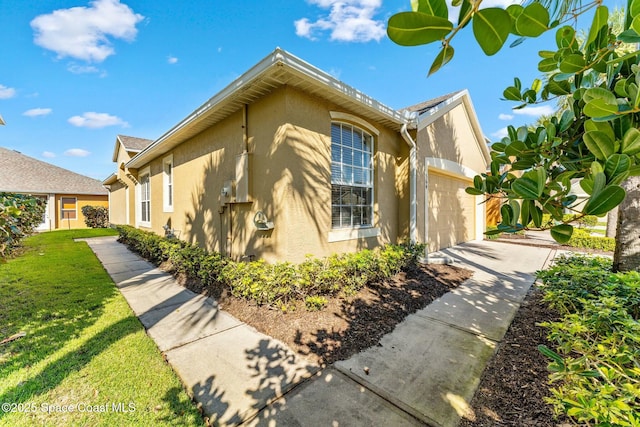 view of home's exterior with a yard, driveway, an attached garage, and stucco siding