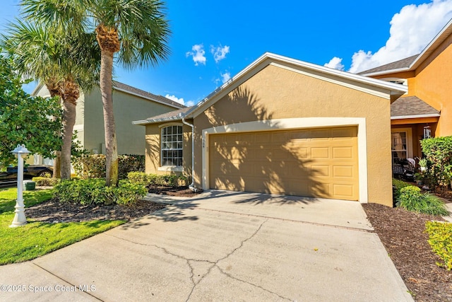 single story home with driveway, an attached garage, and stucco siding