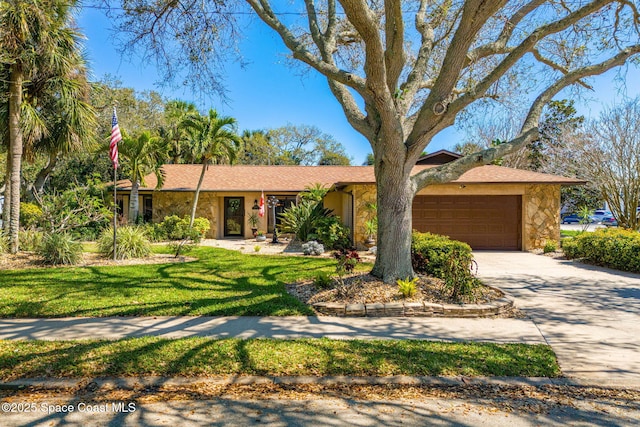 single story home with stone siding, a front lawn, an attached garage, and driveway