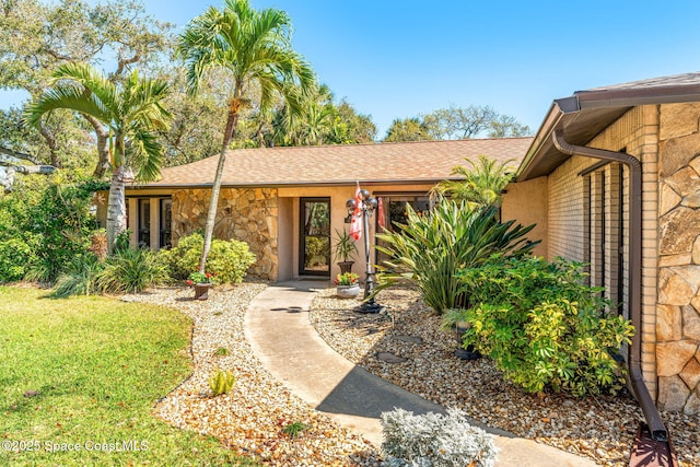 property entrance featuring stone siding and roof with shingles