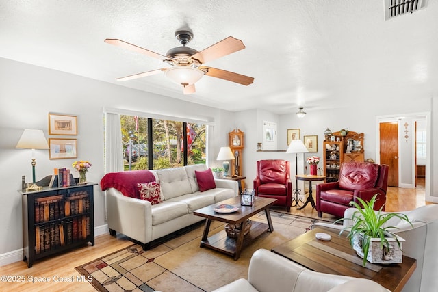 living room with baseboards, light wood finished floors, visible vents, and a ceiling fan