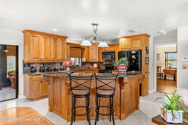 kitchen featuring visible vents, dark stone counters, decorative backsplash, black appliances, and light tile patterned flooring