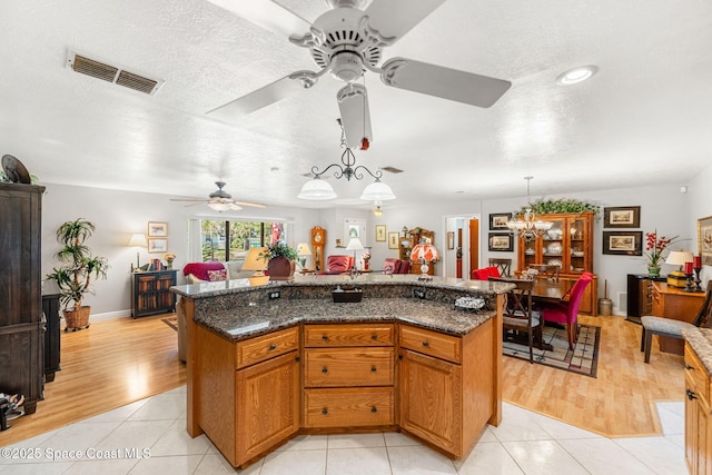 kitchen featuring brown cabinets, visible vents, decorative light fixtures, and light tile patterned floors