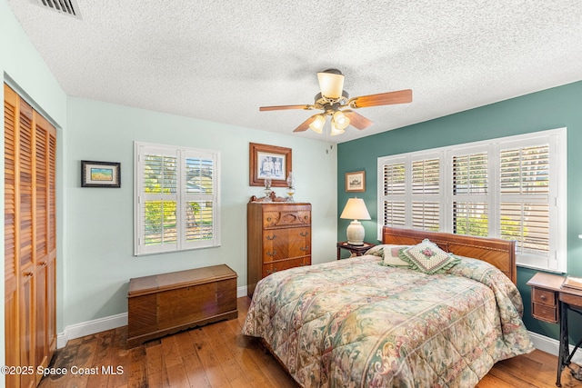 bedroom featuring a closet, visible vents, wood-type flooring, and baseboards