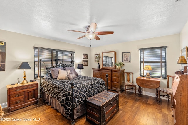 bedroom featuring a ceiling fan, baseboards, a textured ceiling, and hardwood / wood-style floors