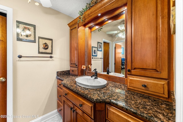 bathroom with a ceiling fan, baseboards, a textured ceiling, and vanity