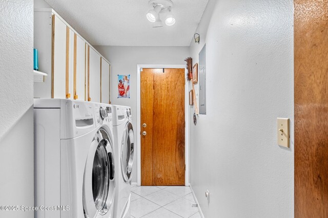 washroom with light tile patterned floors, a textured ceiling, cabinet space, and washer and dryer