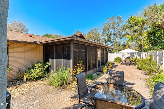 view of patio / terrace with a sunroom, outdoor dining area, and a fenced backyard