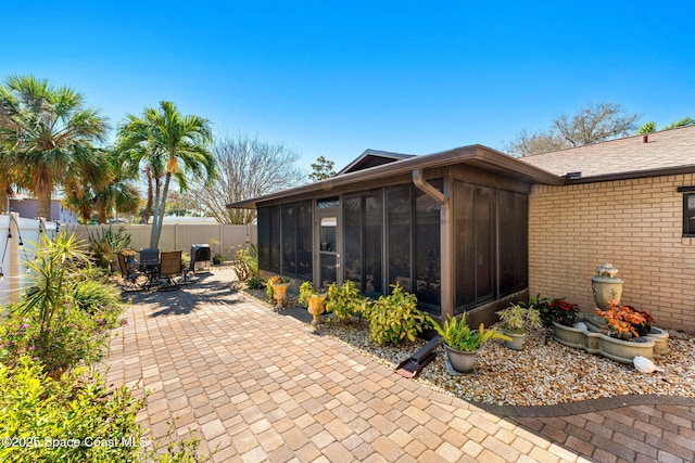 exterior space with outdoor dining space, a fenced backyard, and a sunroom