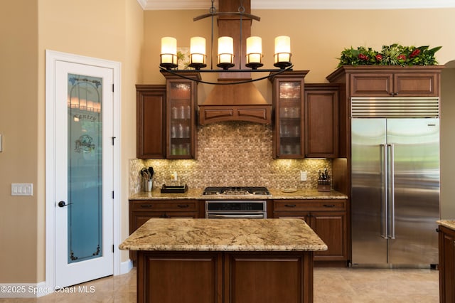 kitchen featuring appliances with stainless steel finishes, a center island, custom range hood, and glass insert cabinets