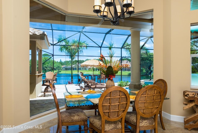 dining space with a water view, a sunroom, baseboards, and an inviting chandelier