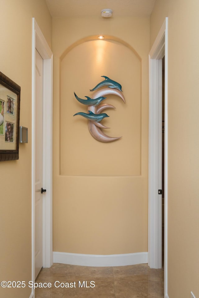 corridor with light tile patterned floors and baseboards