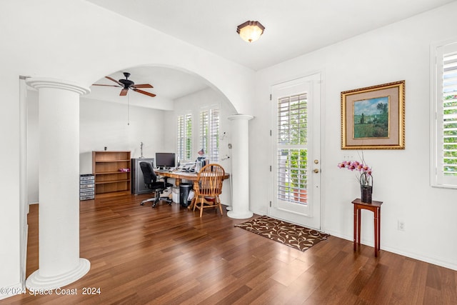 home office featuring arched walkways, wood finished floors, a ceiling fan, and ornate columns