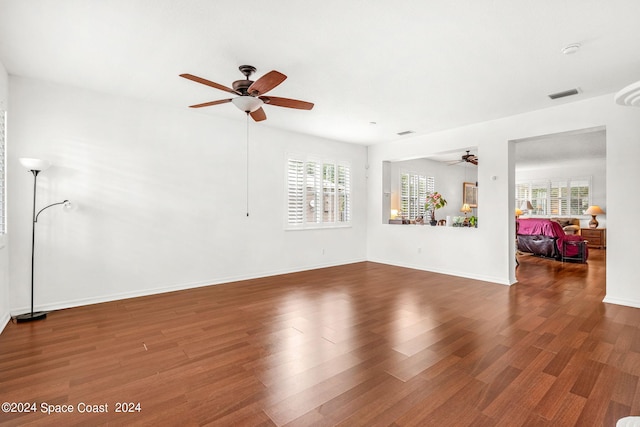 unfurnished living room with a ceiling fan, visible vents, baseboards, and wood finished floors