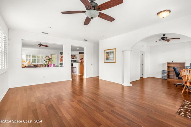 living room featuring baseboards, visible vents, arched walkways, and wood finished floors