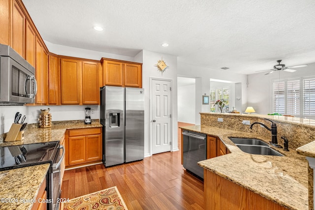 kitchen with appliances with stainless steel finishes, a healthy amount of sunlight, a sink, and wood finished floors