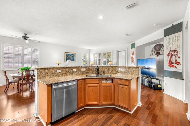 kitchen featuring visible vents, brown cabinetry, dishwasher, dark wood-style floors, and a sink