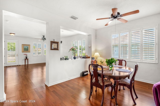 dining space with visible vents, a ceiling fan, a textured ceiling, wood finished floors, and baseboards