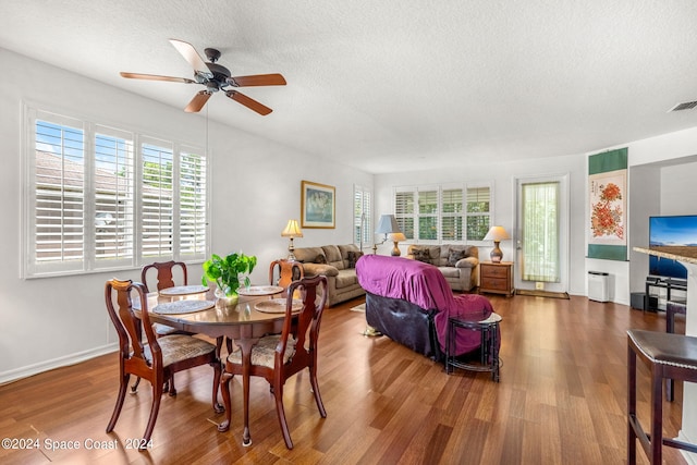 dining area with a textured ceiling, wood finished floors, a wealth of natural light, and baseboards