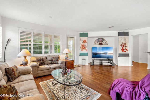 living room featuring a textured ceiling, wood finished floors, and visible vents